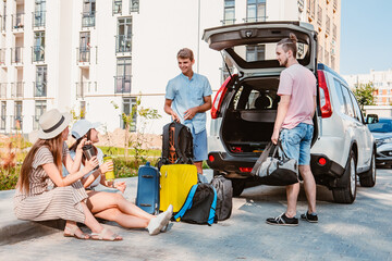 friends load car trunk with baggage