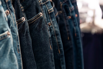 Jeans fabric background dark blue with copy space, a lot of clothes pants hanging are sold on the shop window