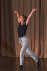 A young dancer rehearsing a dance on stage.