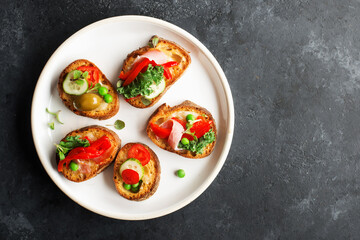 Finger food. Appetizing crostini with baked capsicum, green peas, bacon, kale and lettuce as a festive snack. Top view,
