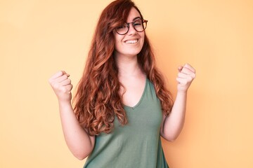Young beautiful woman wearing casual clothes and glasses screaming proud, celebrating victory and...