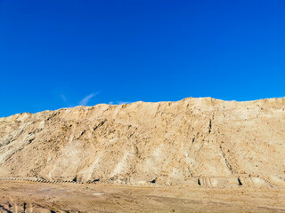 Fototapeta na wymiar A mountain of wet yellow sand and a blue, clear sky.