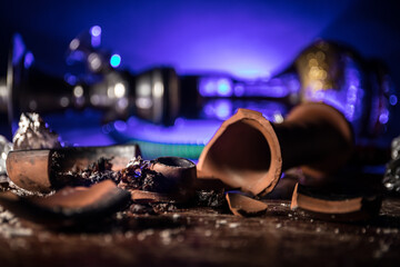 Hookah hot coals on shisha bowl making clouds of steam at Arabian interior. Shisha concept. Broken shisha bowl on wooden table. Dark atmosphere with light. Selective focus.