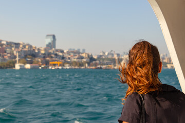 redhead woman looking to the Istanbul on the boat at sunset