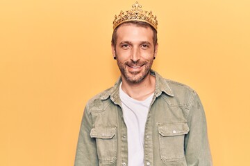 Young handsome man wearing king crown with a happy and cool smile on face. lucky person.
