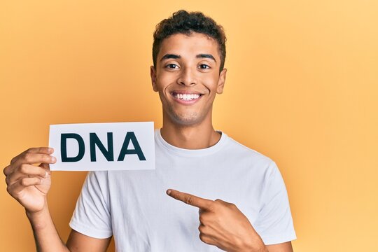 Young handsome african american man holding dna word smiling happy pointing with hand and finger