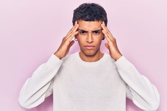 Young african amercian man wearing casual clothes with hand on head, headache because stress. suffering migraine.