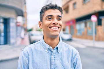 Young latin man smiling happy walking at the city.