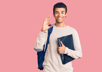 Young african amercian man wearing student backpack holding binder doing ok sign with fingers, smiling friendly gesturing excellent symbol