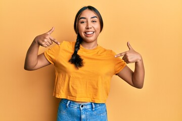 Young latin woman wearing casual clothes looking confident with smile on face, pointing oneself...