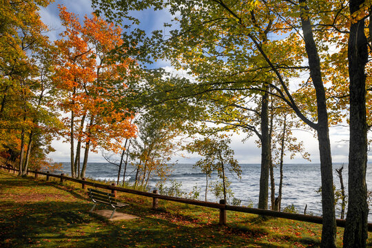 Autumn trees along scenic Superior lake shore with waves hitting rocks.