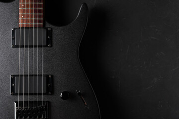 Gray electric guitar close-up on a dark concrete background. Top view and place for your text on the right.
