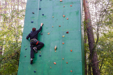 Man climbing the wall.Man climber on an artificial climbing wall in the forest