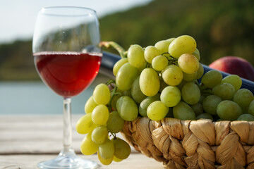 fruit basket and a glass of wine on the wooden picnic pier