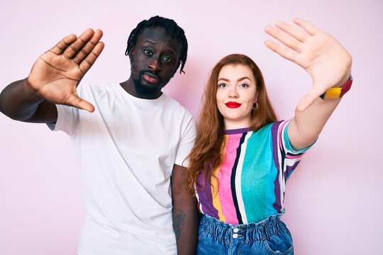 Interracial couple wearing casual clothes doing frame using hands palms and fingers, camera perspective