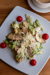 Caesar salad with chicken breast in a plate on the table. Appetizing dish. Close-up. Top view. Vertical.