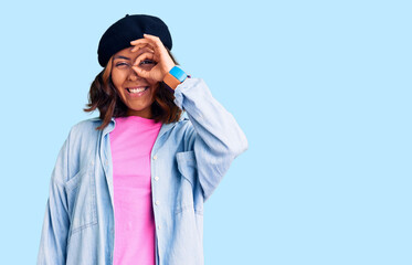 Young beautiful mixed race woman wearing french look with beret doing ok gesture with hand smiling, eye looking through fingers with happy face.