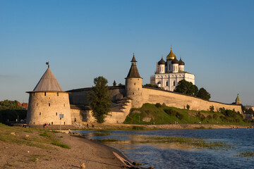 Fototapeta na wymiar Pskov Kremlin view from river Pskova creek. Towers, wall and Trinity cathedral on background.