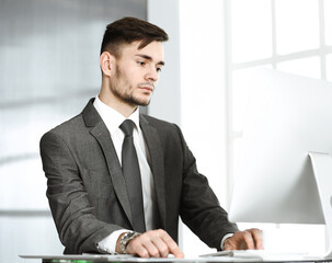 Businessman working with computer in modern office. Headshot male entrepreneur or manager at workplace. Business concept