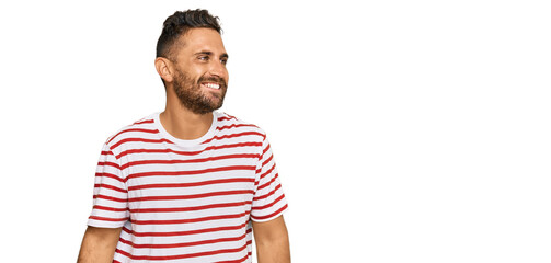 Handsome man with beard wearing striped tshirt looking away to side with smile on face, natural expression. laughing confident.