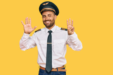 Handsome man with beard wearing airplane pilot uniform showing and pointing up with fingers number eight while smiling confident and happy.