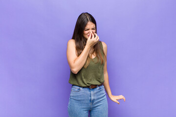 youn pretty woman feeling disgusted, holding nose to avoid smelling a foul and unpleasant stench