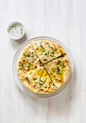 Pita bread with cheese and herbs on white wooden background