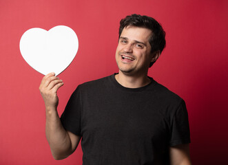 Brunette guy with heart shape on red background