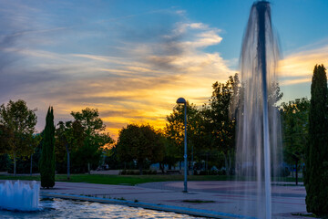 Fototapeta premium A beautiful and colorful sunset in a park with a fountain in Madrid practically empty due to the confinement under which this city on October 10, 2020. Spain