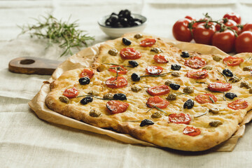 Tasty italian focacchia bread on table with tomatoes and olives