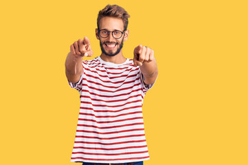 Naklejka premium Handsome blond man with beard wearing casual clothes and glasses pointing to you and the camera with fingers, smiling positive and cheerful