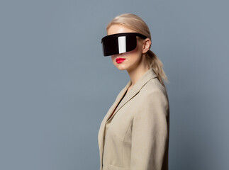 Style blonde in futuristic VR glasses on gray background