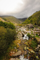 Naklejka na ściany i meble stream runs between rocks with a mountain in background (Louriga - Portugal)