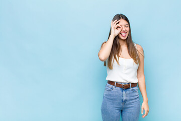 youn pretty woman smiling happily with funny face, joking and looking through peephole, spying on...