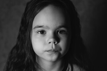 A little girl looks into the eyes of a black and white photo