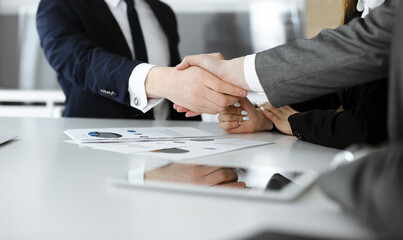 Unknown businessmen and woman sitting, working and discussing questions at meeting in modern office, close-up