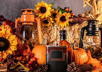 autumn still life with pumpkins sunflowers and gas lanterns with whiskey flask and bottle of brandy 