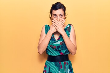 Young beautiful hispanic woman wearing casual dress shocked covering mouth with hands for mistake. secret concept.