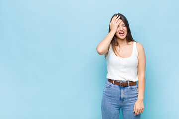 youn pretty woman laughing and slapping forehead like saying d’oh! I forgot or that was a stupid...