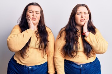 Young plus size twins wearing casual clothes touching mouth with hand with painful expression because of toothache or dental illness on teeth. dentist