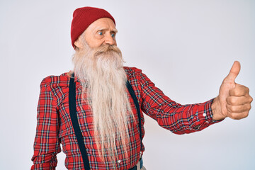 Old senior man with grey hair and long beard wearing hipster look with wool cap looking proud,...