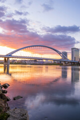 Fototapeta premium Long exposure Apollo bridge over river Danube in Bratislava, Slovakia. Sunset, golden hour, dramatic skies. High rise buildings, travel destination