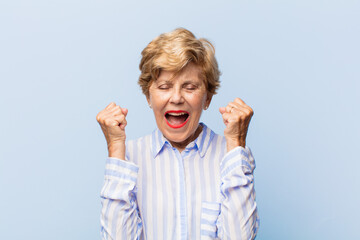 old pretty woman feeling shocked, excited and happy, laughing and celebrating success, saying wow!