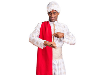 African handsome man wearing tradition sherwani saree clothes in hurry pointing to watch time,...