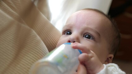Closeup view of mother feeding her baby milk from bottle