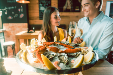 Fresh oysters and crabs served on ice at the table of a romantic young couple