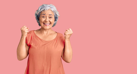 Senior woman with gray hair wearing orange tshirt very happy and excited doing winner gesture with arms raised, smiling and screaming for success. celebration concept.