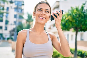 Young cauciasian fitness woman wearing sport clothes training outdoors listening to voice message on the phone