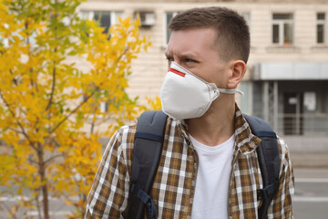 Young man in a protective mask on an autumn background