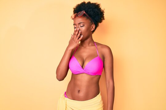 Young african american woman wearing bikini bored yawning tired covering mouth with hand. restless and sleepiness.
